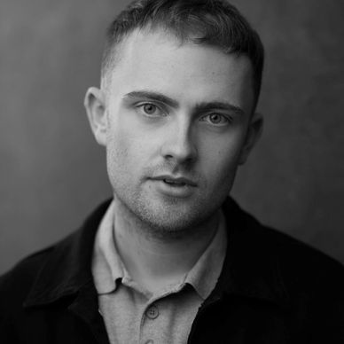 Close-up portrait of a young man with blue eyes and short hair.