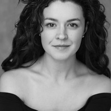 Portrait of a woman with dark curly hair and a slight smile, wearing an off-shoulder black top.