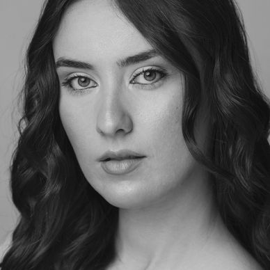 Close-up portrait of a woman with wavy dark hair and natural makeup.