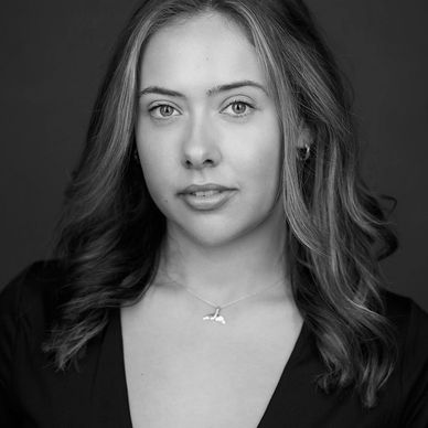 Young woman with light brown hair and green eyes looks confidently at the camera.