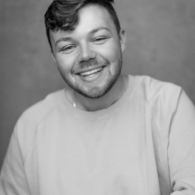 Smiling young man wearing a bright yellow sweatshirt.