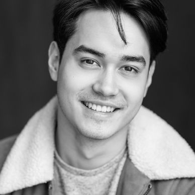 Smiling young man in a brown jacket with a shearling collar.