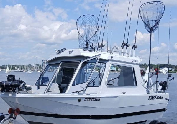 White fishing boat with nets and rods on water.