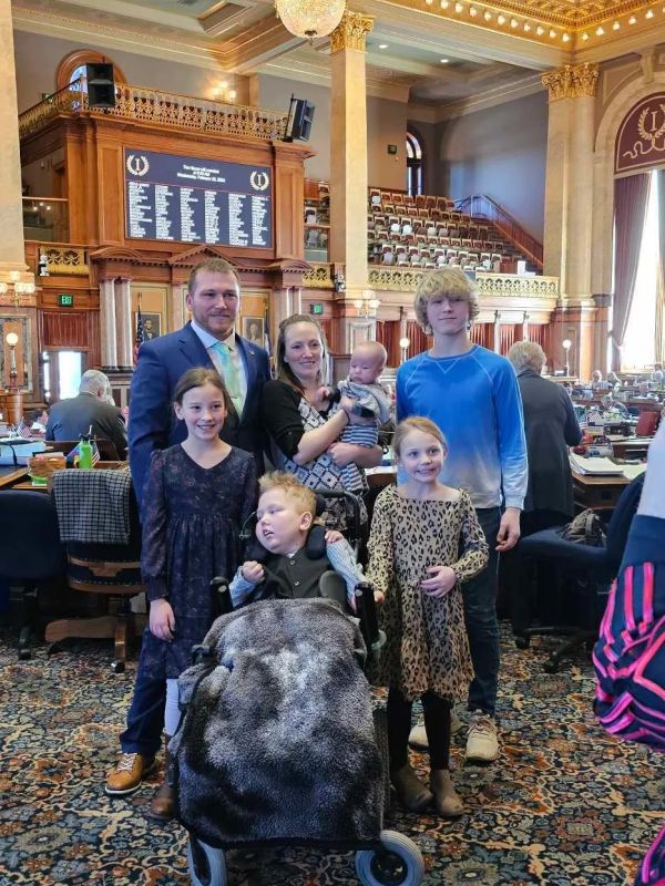 Family posing in a grand legislative chamber.
