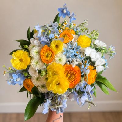 A vibrant bouquet of yellow, orange, white, and blue flowers.