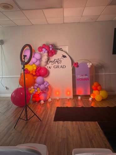Decorative graduation and empowerment photo setup with balloons and lighting.