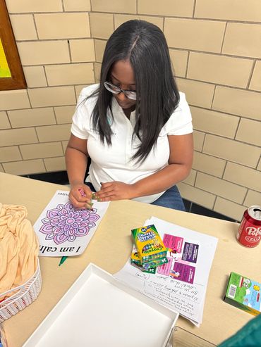 Woman coloring a mandala on paper.