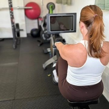 Woman exercising on a rowing machine in a gym.