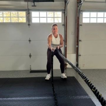Woman exercising with battle ropes in a garage gym.