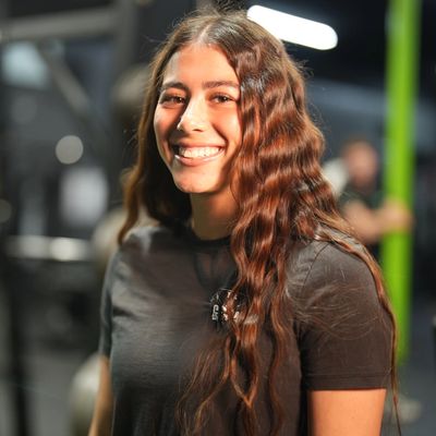 Smiling woman with long wavy hair in a gym.