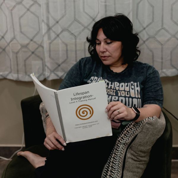 Woman reading a Lifespan Integration training manual while sitting on a couch.