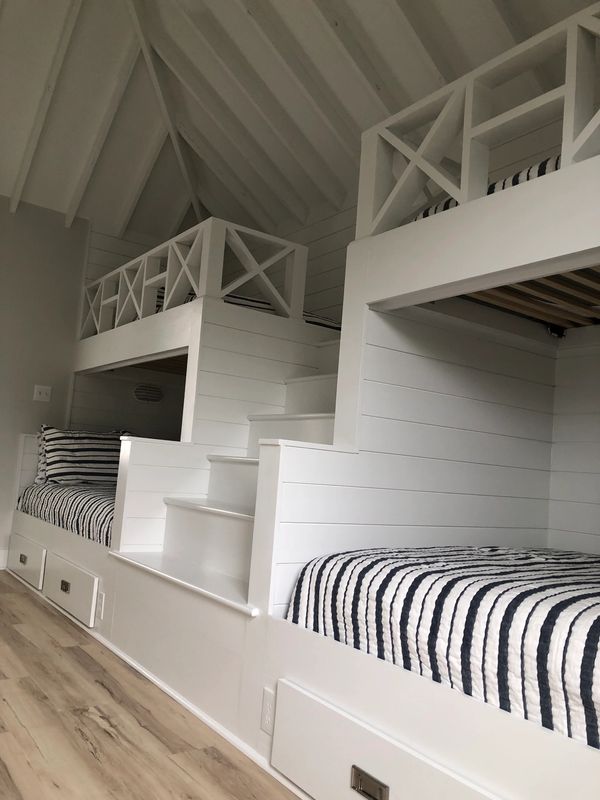 White bunk beds with striped bedding in a cozy room.