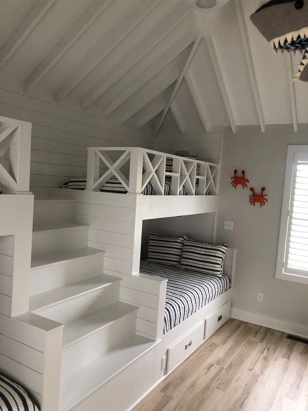 White bunk beds with striped bedding in a cozy room.