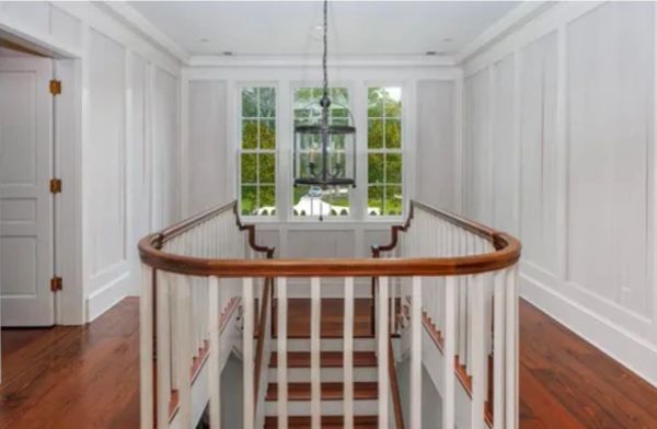 Interior hallway with white paneling and wooden floor.