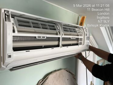 Technician repairing an air conditioner inside a room.