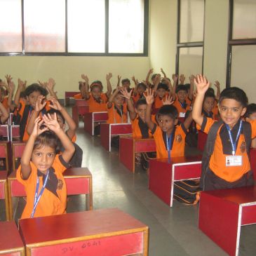 Children in classroom raising hands.