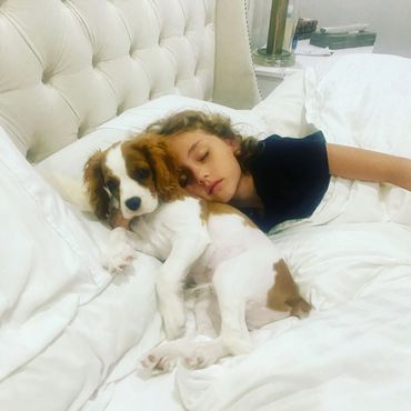 Girl sleeping in bed with Cavalier King Charles puppy