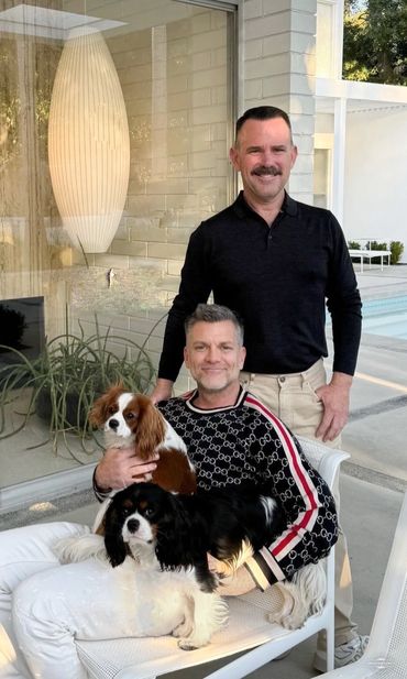 Two men posing with their Cavalier King Charles dogs 