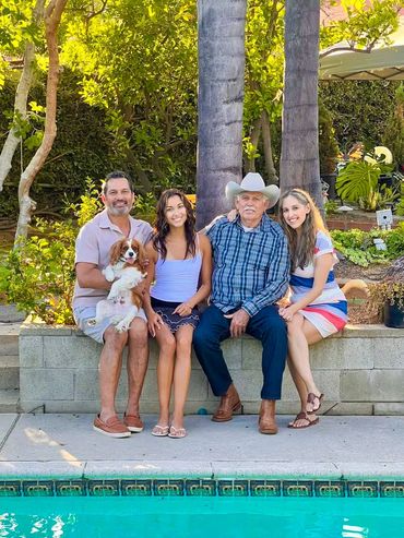 Family and cavalier dog sitting by pool