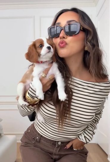 Woman holding a Cavalier King Charles Spaniel puppy blowing a kiss