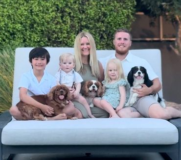 Family with small children’s sitting with Cavalier King Charles Spaniel dogs