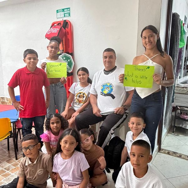 Group of children and an adult holding thank you signs in a classroom.