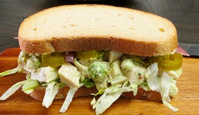 A sandwich with chicken salad and jalapeños on white bread.