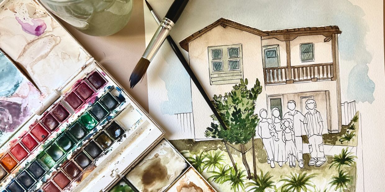 Watercolor painting in progress of a house and family with paintbrushes and palette.