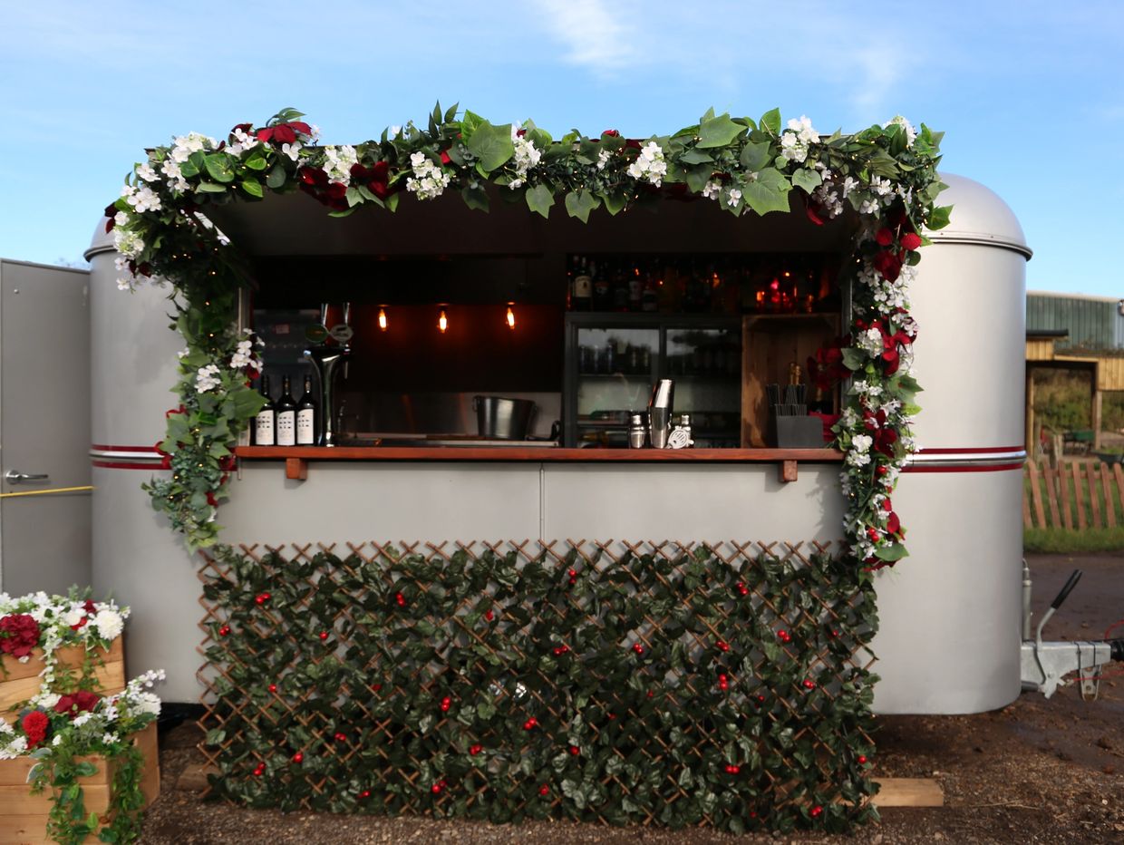 Outdoor bar decorated with green leaves and red and white flowers.