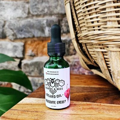 A single bottle of beard oil in the scent Chocolate Cherry sitting on a table, next to a basket.