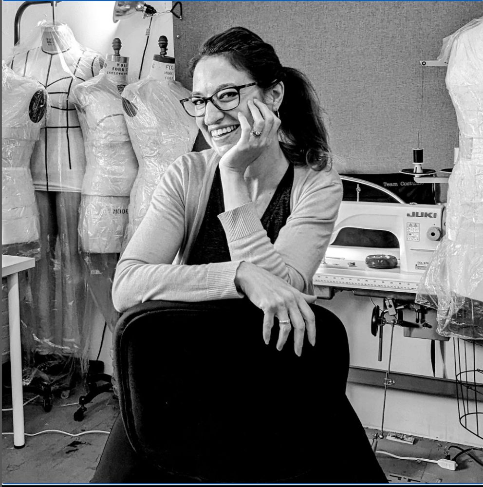 Sarah sitting, surrounded by dress forms and sewing machines.