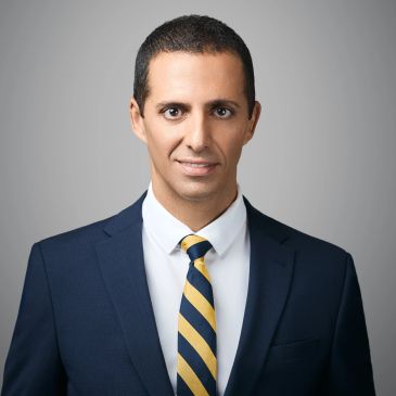 Professional man in suit and striped tie against gray background.