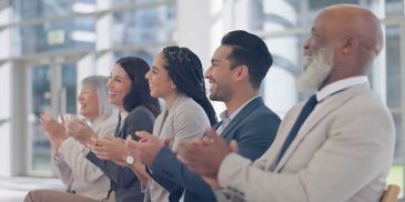 A group of people sitting in a meeting and clapping.