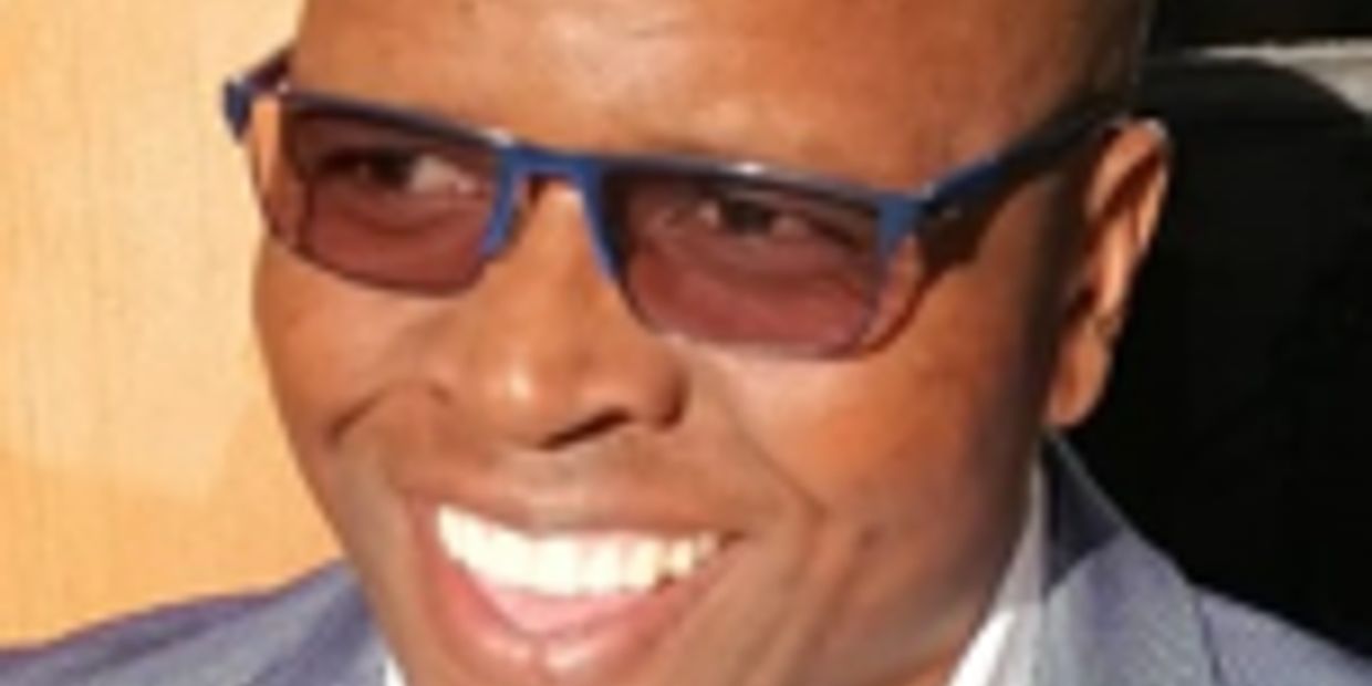 Smiling man wearing sunglasses and a suit.