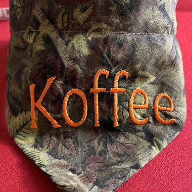 Close-up of fabric with 'Koffee' embroidered in orange thread.