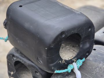 Black plastic buoy with a rope.