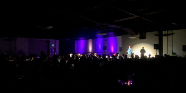 Stand-up comedy show in a dimly lit room.