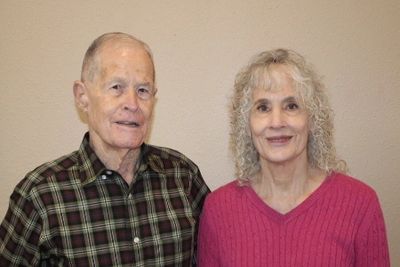 Elderly couple smiling against a plain background.