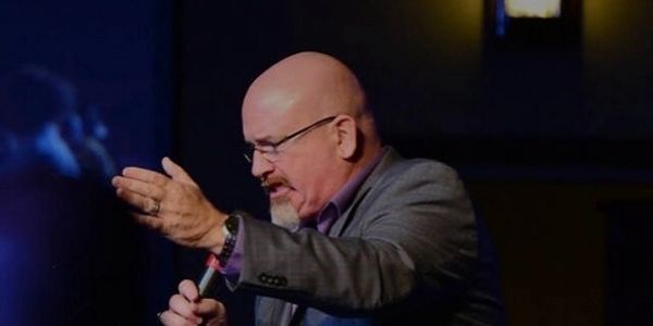 A man passionately speaking into a microphone on stage.