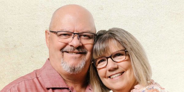 Smiling middle-aged couple wearing glasses posing together.