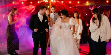 Bride and groom dancing with guests at a lively wedding reception.