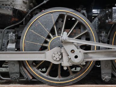 Close-up of a steam locomotive's driving wheel and connecting rods.