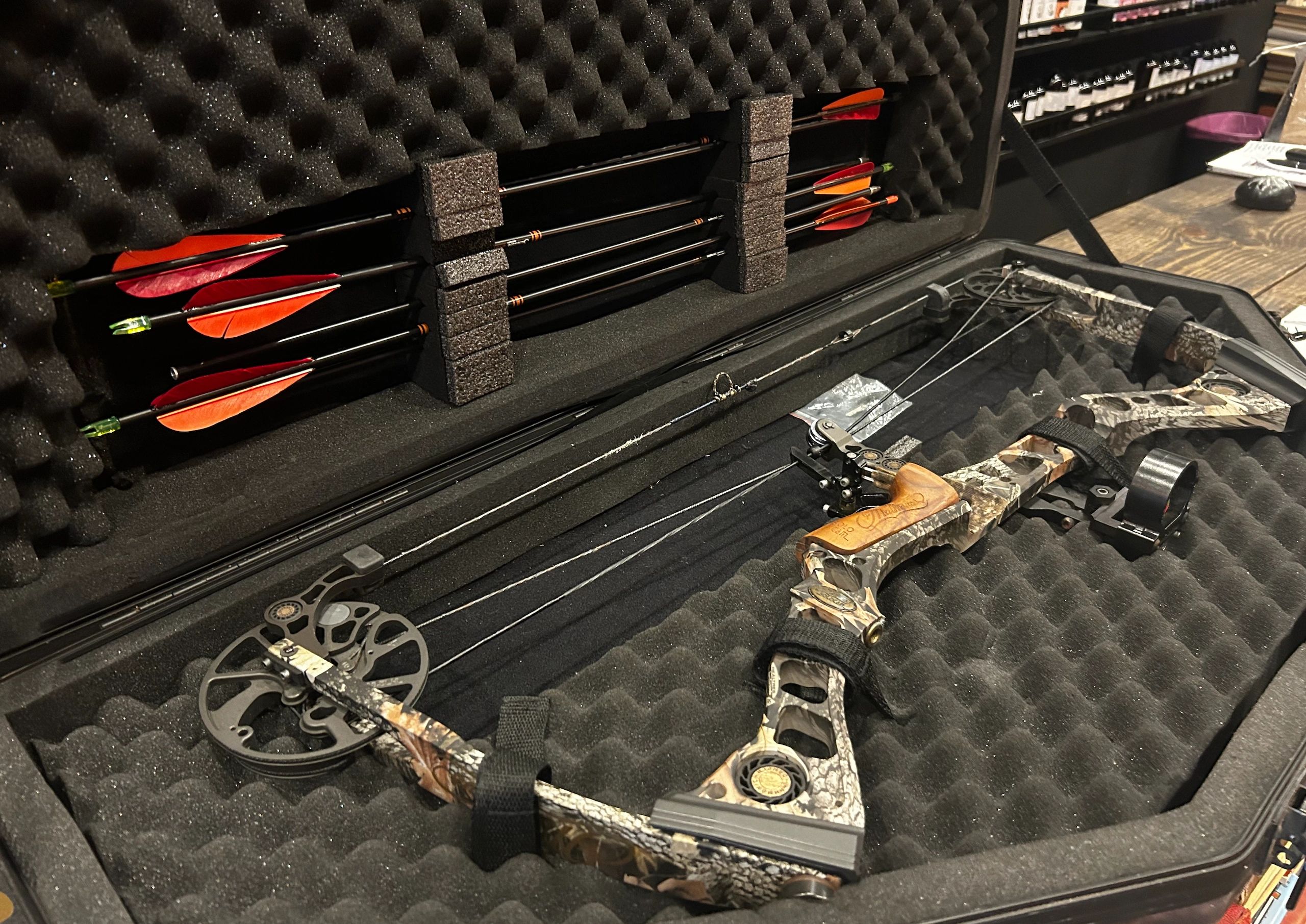 Compound bow and arrows stored in a foam-lined case.