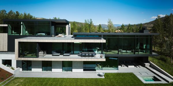 Modern luxury house with large glass windows and a pool.