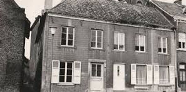 Black and white photo of a vintage two-story building with shuttered windows.