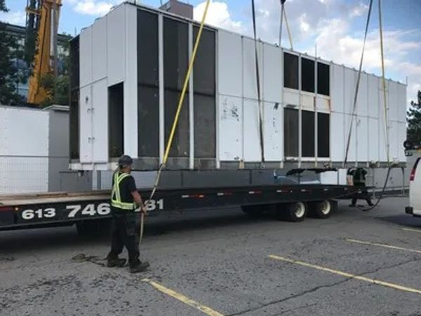 construction worker hoisting heavy unit