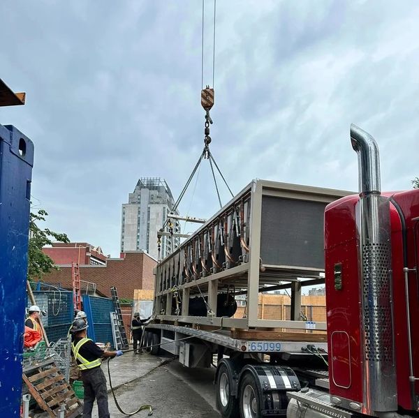construction workers rigging heavy equipment to be lifted on to building