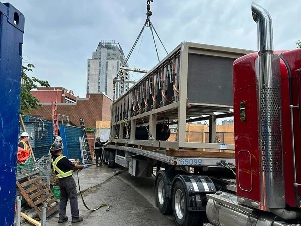Construction workers rigging ac unit to lift onto roof