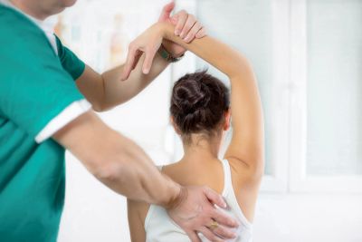 Physical therapist helping patient with shoulder stretch.