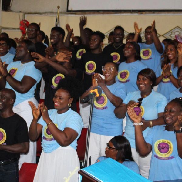 Group of people clapping and smiling in matching light blue shirts.